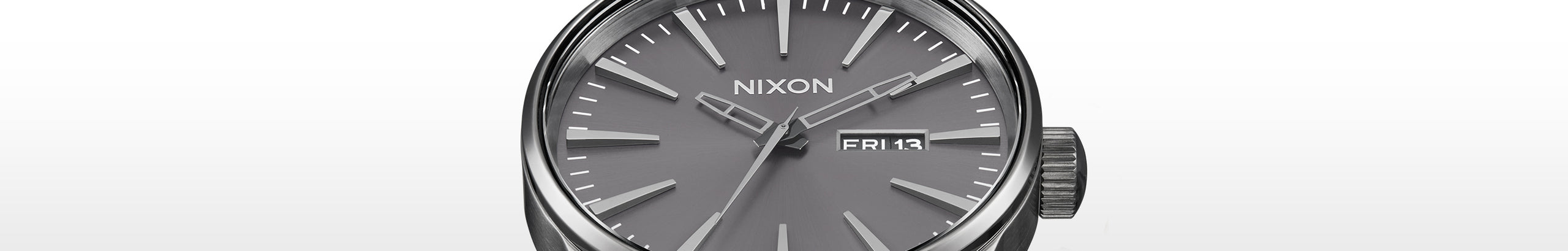 Close-up of a Nixon Sentry watch with a gunmetal grey dial, silver hands, and markers, displaying "FRI 13".